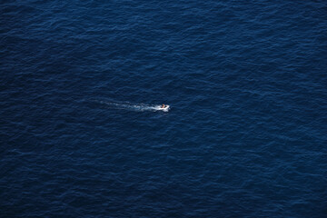 Fototapeta premium Small boat in the middle of the blue ocean.