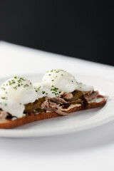sandwich with poached egg and stew, drizzled with cheese and herbs