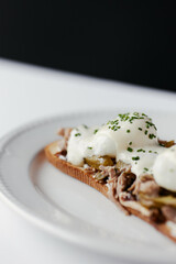 sandwich with poached egg and stew, drizzled with cheese and herbs