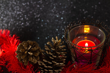 Uma vela acesa com pinhas em um fundo preto brilhante. Decoração natalina.
