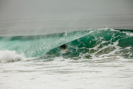 A male surfer navigates the barrel while surfing at Westward in Malibu, California.