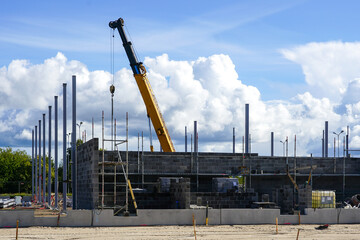 Construction site of a new industrial building with vertical steel columns and a telescopic crane