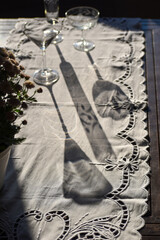 mesa com taças vazias  ao sol. Sombra de taças de cristal sobre toalha branca. Fim de festa. 
