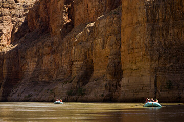 People rafting on a river in a canyon.