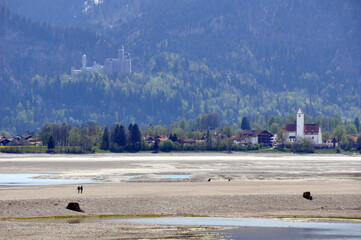 trockener forggensee bei füssen im allgäu / süddeutschland im frühjahr bei blauem himmel , mit...