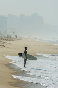 Surfer holding surfboard in Barra Beach, Barra da Tijuca, Rio de Janeiro, Brazil