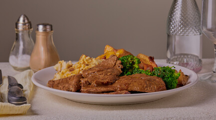 Beef sunday roast in a white setting with condiments in the background.