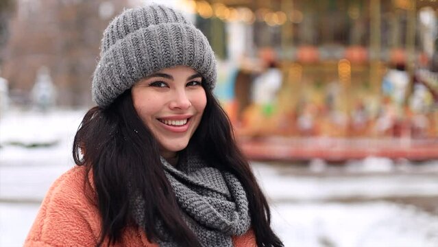 Outdoor close-up portrait of long haired woman with romantic smile chilling in park in winter day.   