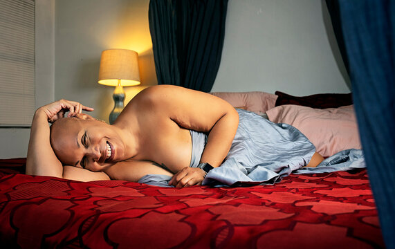 Bald Black woman laying on bed