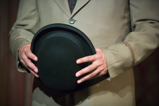 A man holding a hat in front of his midsection.
