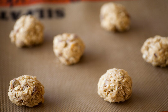 Balls of freshly made organic oatmeal cookie dough sit on a cookie sheet in a kitchen in Seattle, Washington.