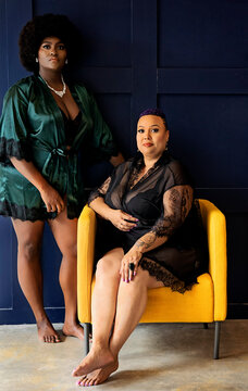 Two Black Women standing and sitting in yellow chair
