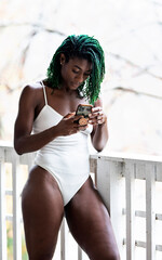 Black woman with green dreadlocks on the patio holding cell phone