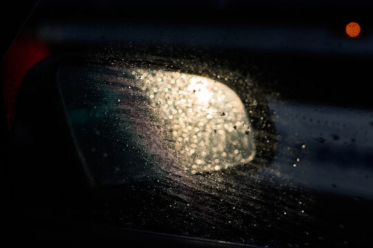 Drops on a car window, the sun reflects off the rearview mirror