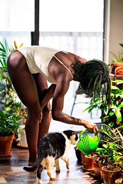 Black woman with green dreadlocks caring for her plants in her house