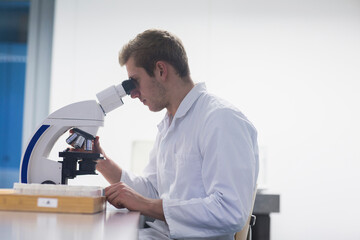 Young male scientist looking through microscope in lecture room, Freiburg Im Breisgau, Baden-Württemberg, Germany