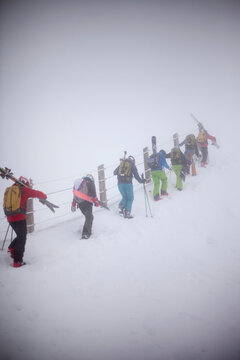 Group if skiers carrying ski gear on mountain slope