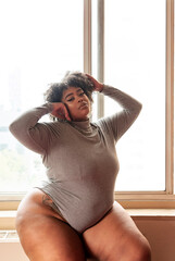 Plus size Black Woman standing in front of a window