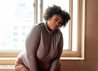 Plus size Black Woman standing in front of a window