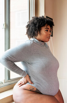 Plus size Black Woman standing in front of a window