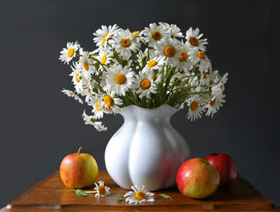 Vase with the flowers and apples on a table