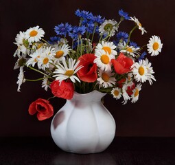 Wild flowers in a vase against a dark background