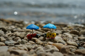 Figurines of two ladybirds with umbrellas on the river bank. A romantic couple. A symbol of love. Feelings and emotions.