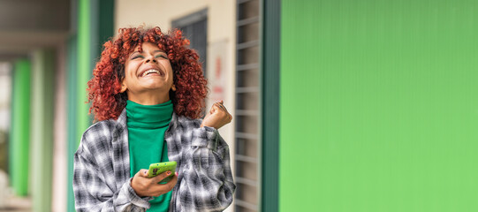 girl with mobile phone in the street excited with happiness