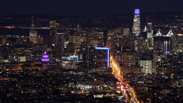 Zoom timelapse of cityscape at night with vivid, neon lighting and ocean shore behind. Motion wallpaper wit iconic scenery of San Francisco with busy traffic along the freeway. High quality 4k footage