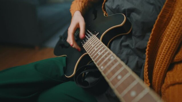 Girl playing semi-acoustic guitar at home.