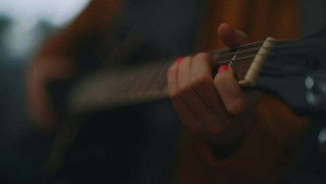 Teenage girl learning to play semi-acoustic guitar.