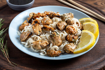 mussels with noodles boiled in a plate with spices on a wooden background