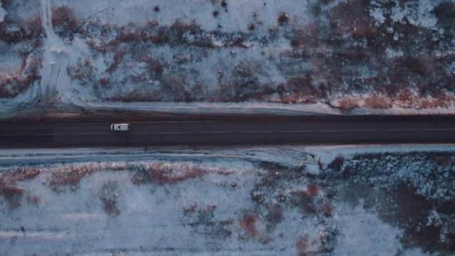 Aerial photography of the highway in winter along the forest at sunset, car traffic in winter.