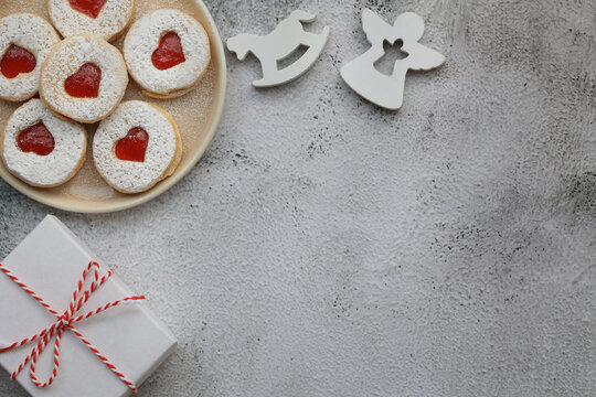 Christmas cookies with a heart filled with strawberry jam, beige plate, white angel and horse, white gift box tied with Christmas rope, place for text