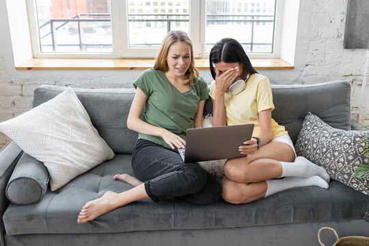 Two Millennial Diverse Girl Friends At Home Watching Movies, Browsing In The Internet, Shopping, Spending Fun Time Together, Chat, Talk. Females Using Technology. Asian And Caucasian Model.