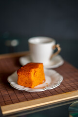 coffee and orange cake on a black background and porcelain tableware on a brown tapere