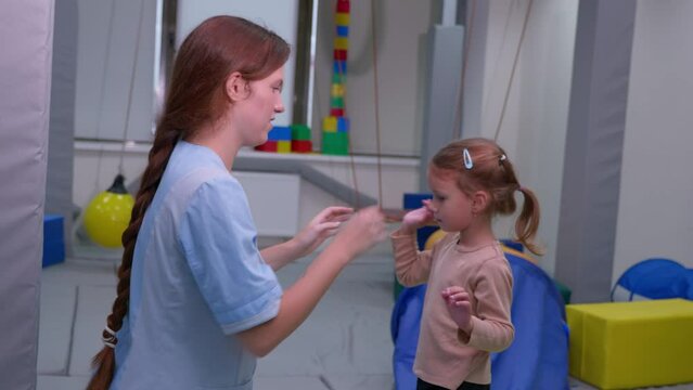 Child girl give five physiotherapist during sensory integration session. The concept of happiness and one team together. Cheerful kid and therapist celebrating teamwork at lesson.
