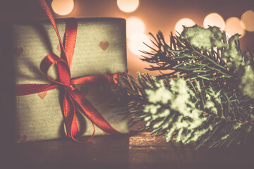Kleines Weihnachtsgeschenk Dekoration mit Lichtpunkten vor Holz und verschneiter Tannenzweig