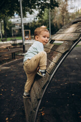 a child is walking on the playground climbing up a wooden slide