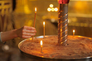 woman in the temple puts candles and prays. religion and spiritual growth. the search for truth and...