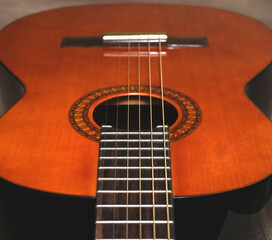 Part acoustic classic orange wooden guitar with black edges, close-up
