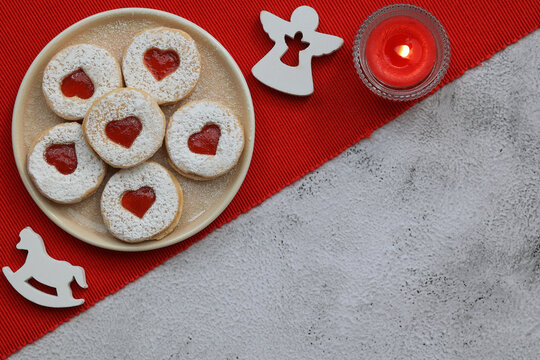 Christmas cookies with hearts filled with strawberry jam, red tablecloth, red candle,white angel and horse Christmas decorations