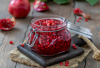 Homemade Pomegranate Tea made from juice and pomegranate seeds in a glass jar. Wooden table, selective focus, horizontal. © Iryna