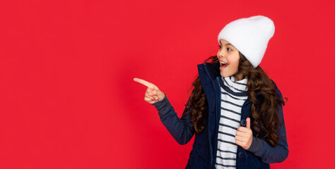 express positive emotion. winter fashion. point finger on copy space. emotional kid