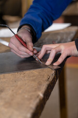 main d'un artisan préparant la coupe de métal et trçant une ligne avec une règle