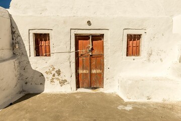 Old wooden entrance to a white house on a sunny day on the Santorini island