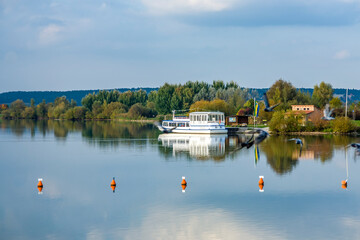 Obraz premium view to Altmuehl river in Bavaria with tourist ship on pier and reflection of coastline
