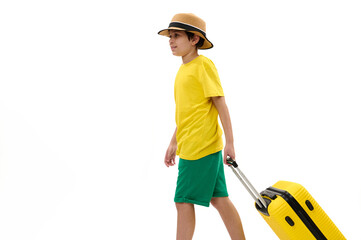 Side portrait of teenager boy in bright yellow t-shirt and green shorts, walking with suitcase, traveling abroad for summer holidays, isolated white background copy space. Journey Tourism Travel Trip
