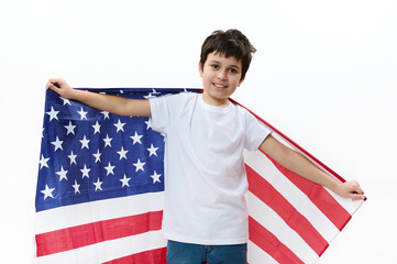 Happy American preteen boy in casual t-shirt and denim jeans, carries USA flag, celebrates Independence Day, July 4th. Citizenship, immigration, emigration, winning green card lottery, freedom concept
