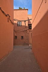 Fototapeta na wymiar Red colored houses in Marrakesh and an alley